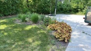 Fort Wayne local spring mulch landscaping with ornamental grasses beside clean driveway.