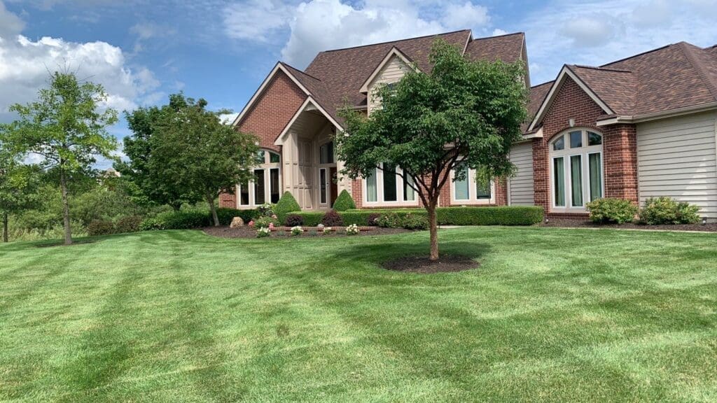Fort Wayne manicured lawn with striped mowing lines in front of large suburban home.
