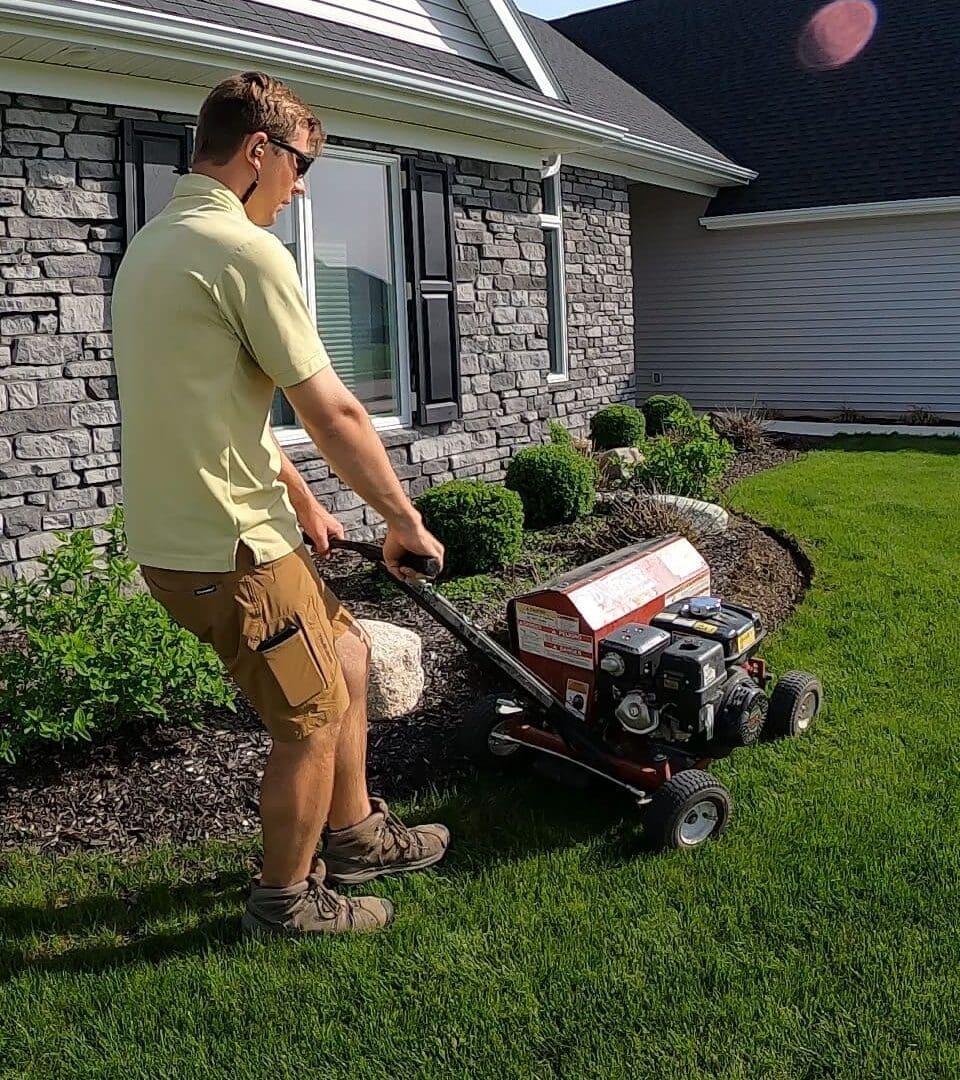 Landscaper edging lawn and mulch beds with power edger in Fort Wayne.