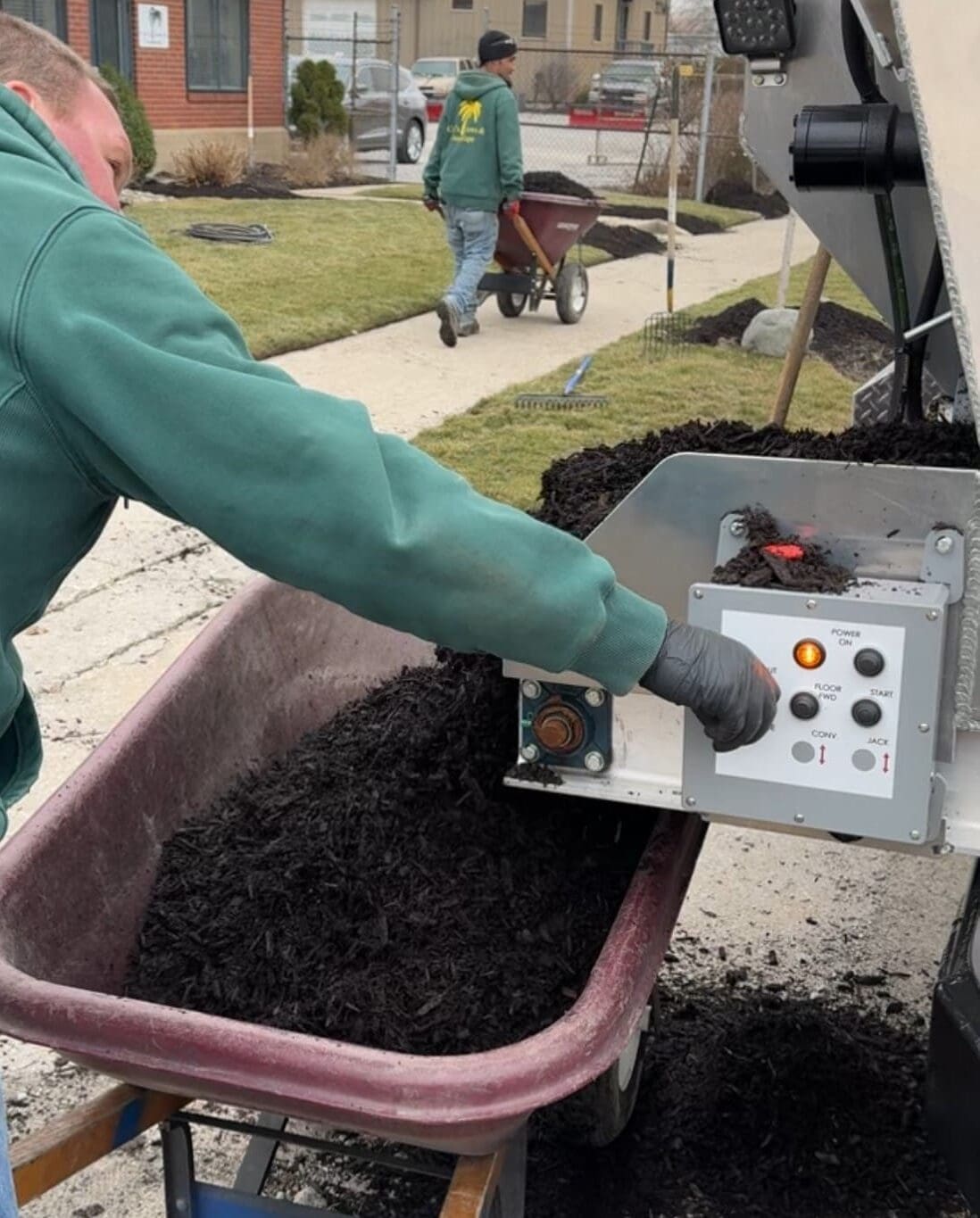 Local Fort Wayne landscaper loading mulch into wheelbarrow with Mulch Mule machine.