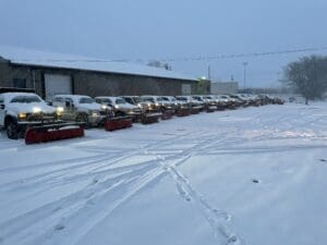 Fort Wayne snowplow trucks lined up outside maintenance garage, ready for snow removal.