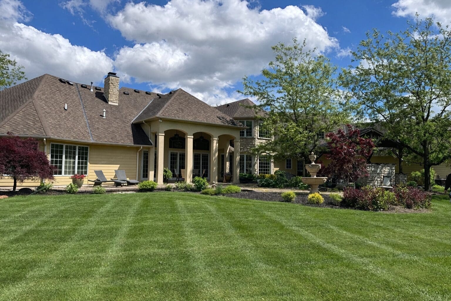 Full-service lawn maintenance in Fort Wayne featuring striped mowing and landscaped luxury home.