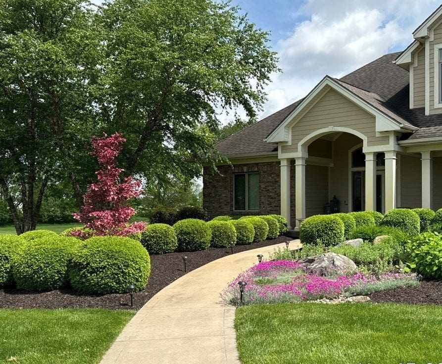 Fort Wayne full-service lawn and landscape maintenance with manicured shrubs, curved walkway, and front entry.