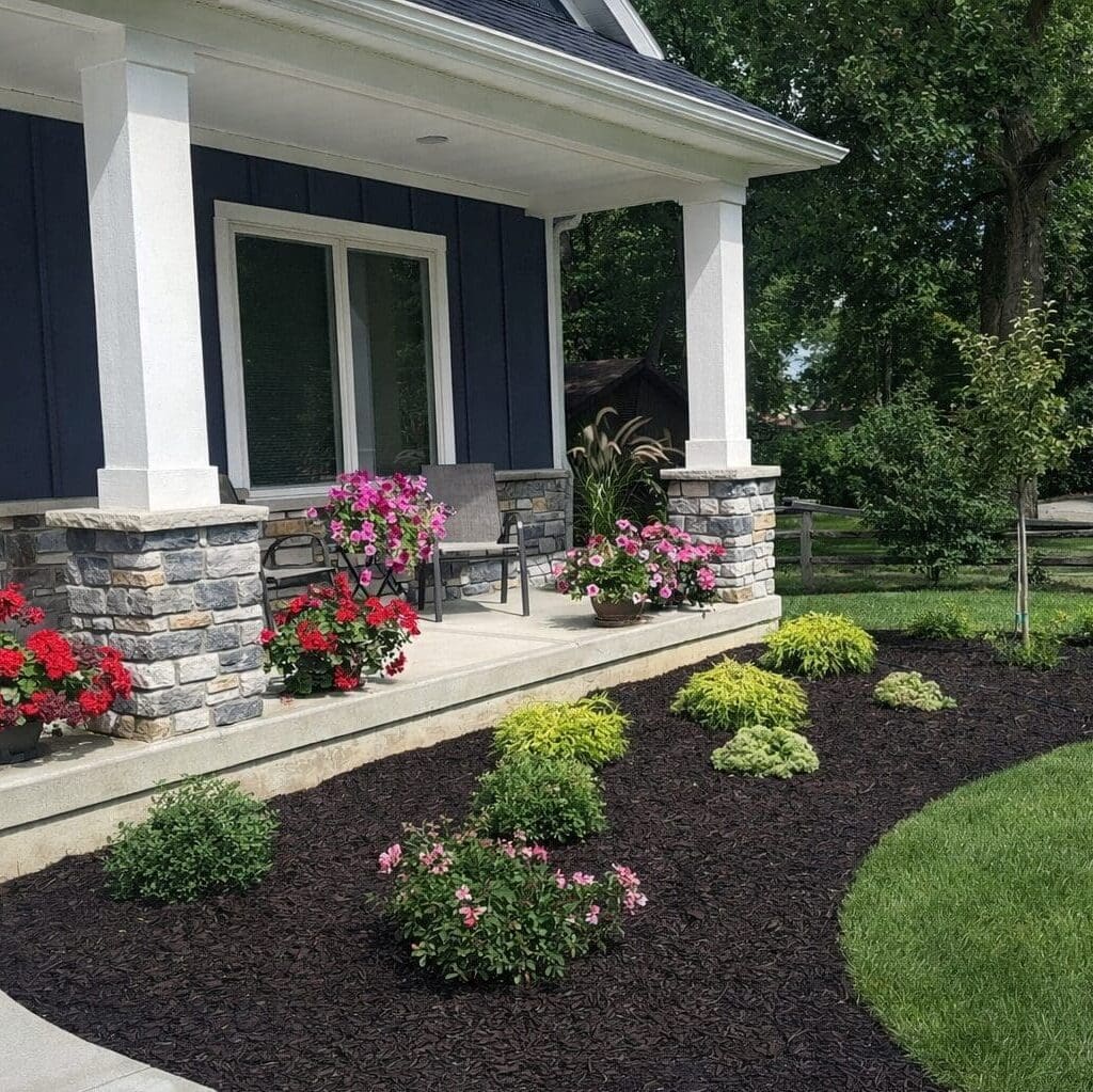 Fort Wayne landscaping with curved mulch bed, shrubs, colorful flowers, and manicured lawn.