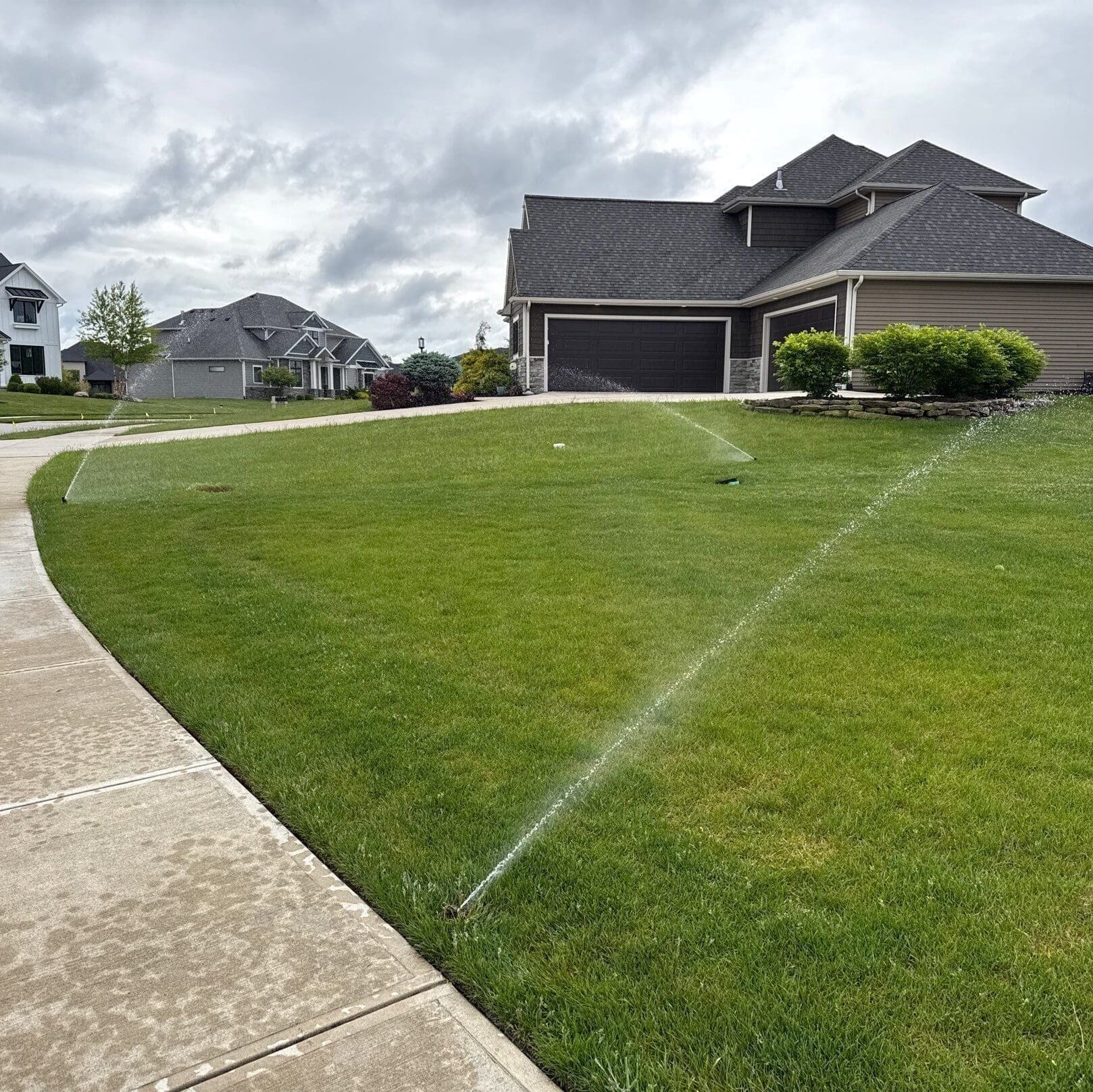 Fort Wayne lawn irrigation sprinklers watering green grass during residential maintenance visit.
