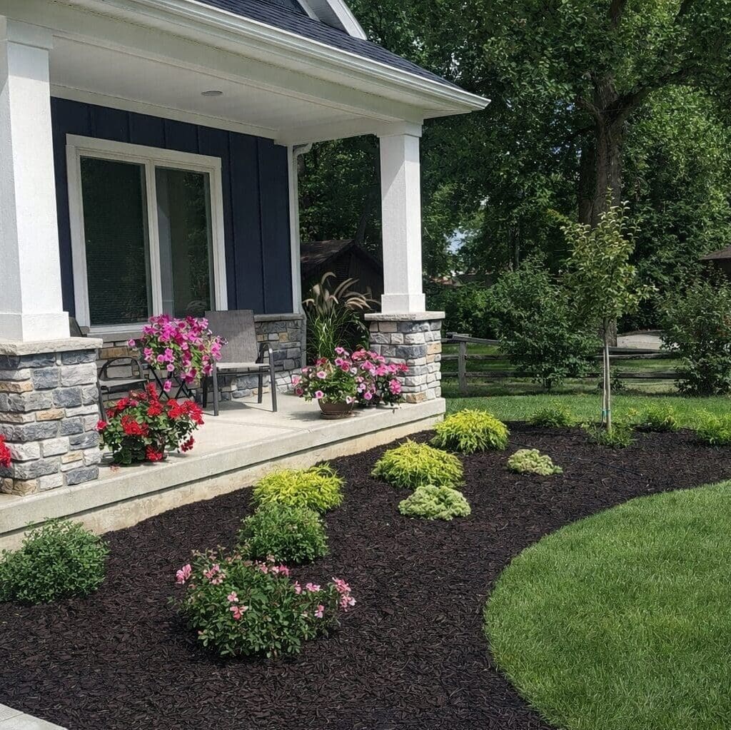 Fort Wayne navy blue home with mulched front yard landscaping, shrubs, and pink flowers.