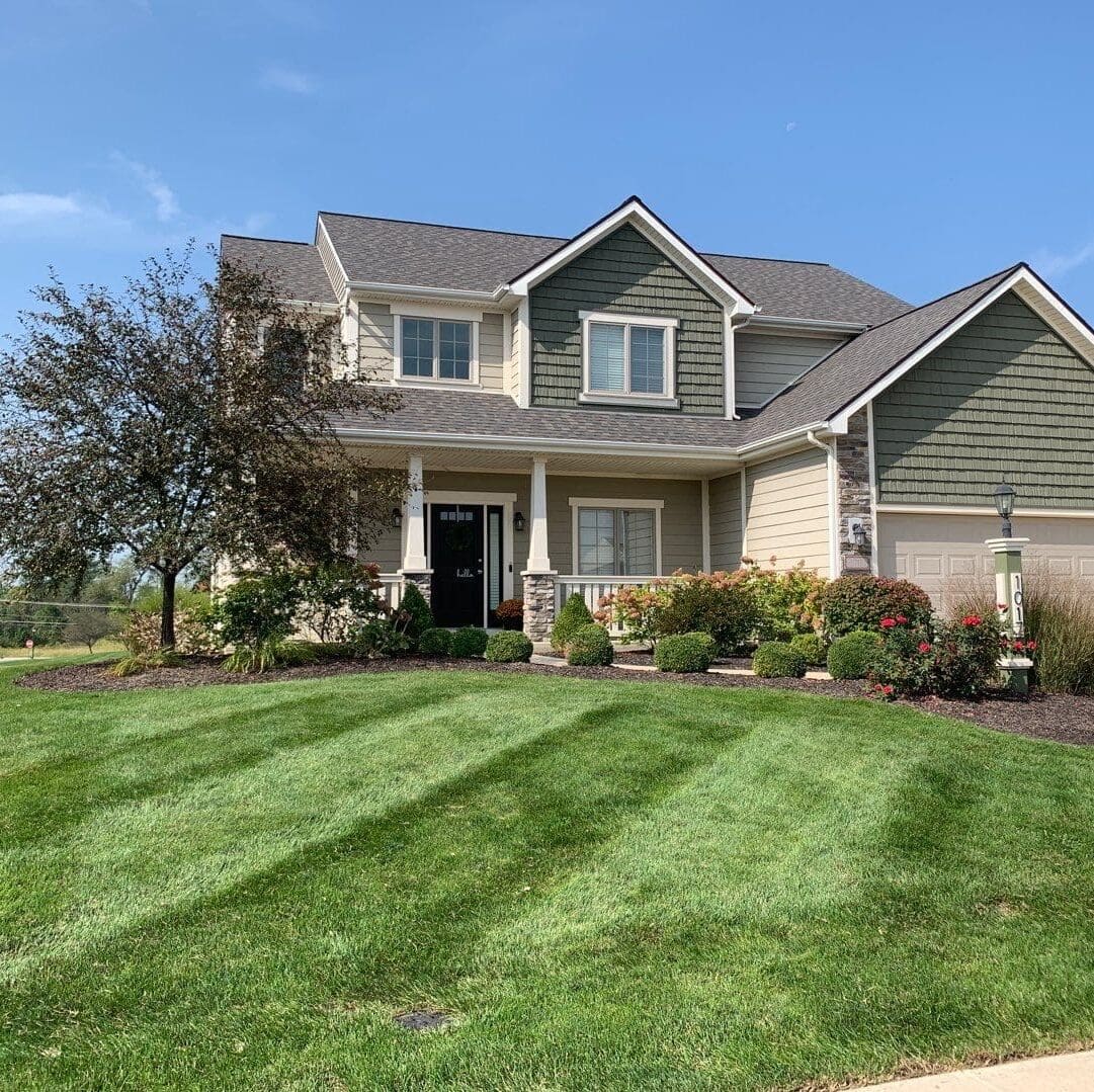 Freshly mowed and mulched Fort Wayne lawn with landscaped shrubs in front of suburban home.