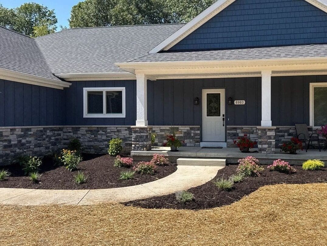 Fort Wayne Modern blue house with stone veneer and new landscaping walkway and mulch beds.