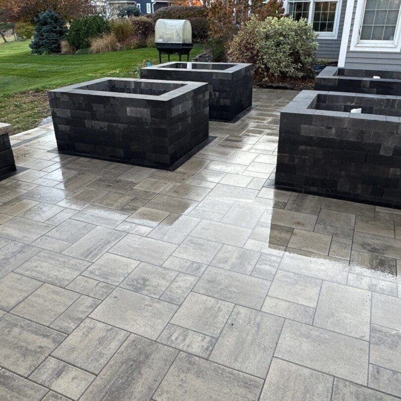 Fort Wayne Modern backyard patio with paver walkway and dark block raised planters near home.